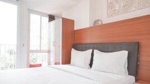 Een hotelkamer met een groot bed, een houten hoofdbord, een nachtkastje met telefoon en afstandsbediening, en een raam met uitzicht op gebouwen.
