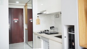 A modern kitchen with white cabinets, a built-in stove, and a coffee machine. - Minimalist And Cozy Studio At Sky House Bsd Apartment (Pagedangan)