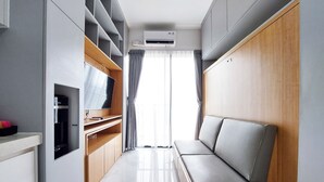 A compact living space with a kitchenette, a seating area, and a large window with curtains. - Minimalist And Cozy Studio At Sky House Bsd Apartment (Pagedangan)