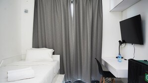 Une chambre d’hôtel avec un lit, un bureau, une chaise, une télévision et un rideau.