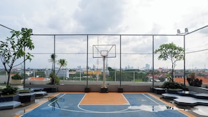 An outdoor basketball court with a net, surrounded by a fence and potted plants. - Best Price 2Br With Pool View Apartment At Taman Melati Surabaya (Surabaya)