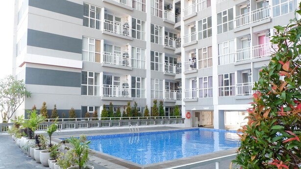 A modern building with a swimming pool, potted plants, and balconies. - Best Price 2Br With Pool View Apartment At Taman Melati Surabaya (Surabaya)