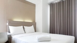 A neatly made bed with white linens, a wooden headboard, and a white chair to the left. - Best Price 2Br With Pool View Apartment At Taman Melati Surabaya (Surabaya)