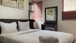 A hotel room with a bed, a nightstand, a dresser, a mirror, and artwork on the wall. - Comfort And Minimalist 2Br At Maple Park Sunter Apartment (Jakarta)