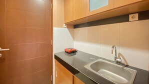 A kitchen with a sink, cabinets, and a door. - Spacious Chic Studio Room Apartment At Gateway Pasteur (Cimahi)