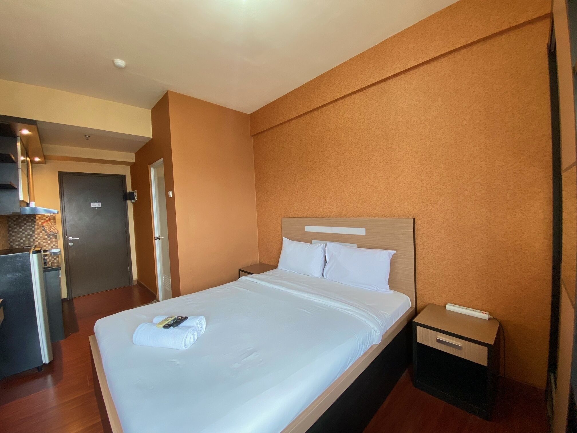 Ein Hotelzimmer mit Bett, Nachttisch, kleinem Tisch und einer Küchenzeile.