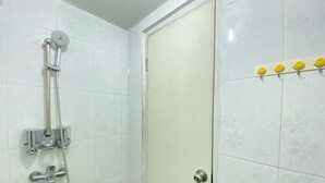 Un baño con ducha, inodoro y una puerta con perchero.
