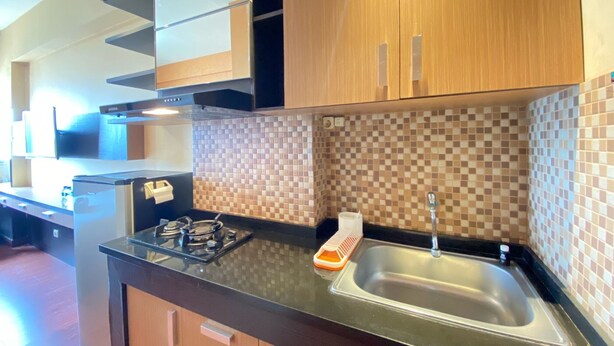 Una cocina moderna con armarios de madera, encimera negra, estufa a gas y un lavamanos.