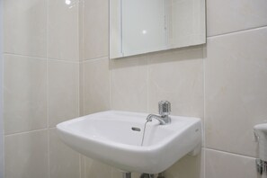A bathroom with a white sink, a mirror above it, and a toilet to the right.