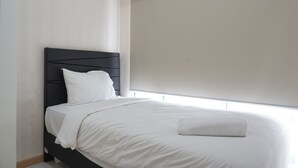 A neatly made bed with white linens and a black headboard in a modern room with a large window.