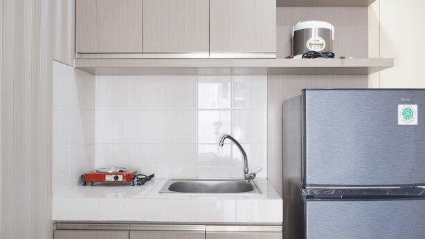 A kitchen with a stainless steel refrigerator, a sink, and a coffee maker on the countertop.