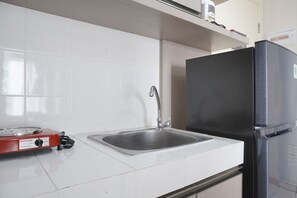 A kitchen with a stainless steel sink, a black refrigerator, and a red electric stove.