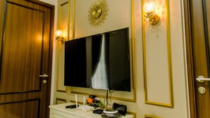 Ein Zimmer mit einem großen Flachbildfernseher an der Wand, einer Holztür und zwei Wandleuchten mit dekorativen Lampenschirm.