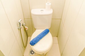 A toilet with a blue towel on the seat, a toilet paper holder, and a shower hose. - Best Deal And Comfy 2Br At Asatti Apartment Vanya Park (Pagedangan)