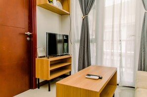 A modern living room with a wooden TV stand, a flat-screen TV, a wooden coffee table, and a sofa. - Best Deal And Comfy 2Br At Asatti Apartment Vanya Park (Pagedangan)