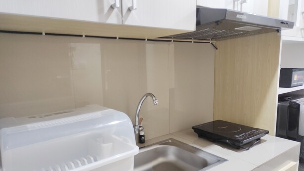 A kitchen with a stainless steel sink, a white countertop, a microwave, and a black induction cooktop.