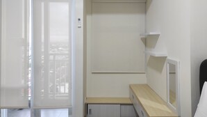 Une chambre dotée d’une porte coulissante donnant sur un balcon, d’un petit bureau et d’un miroir au mur.