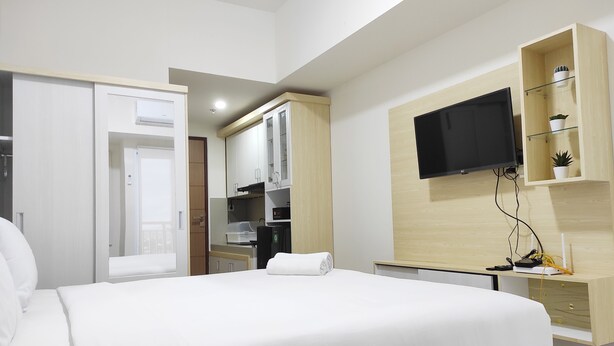 Une chambre d’hôtel comprenant un lit, un téléviseur fixé au mur, un petit coin cuisine et une armoire.
