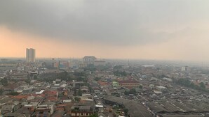 A cityscape with a mix of high-rise buildings and smaller structures, under a hazy sky. - Comfort Studio Room At Margonda Residence 5 Apartment (Depok)