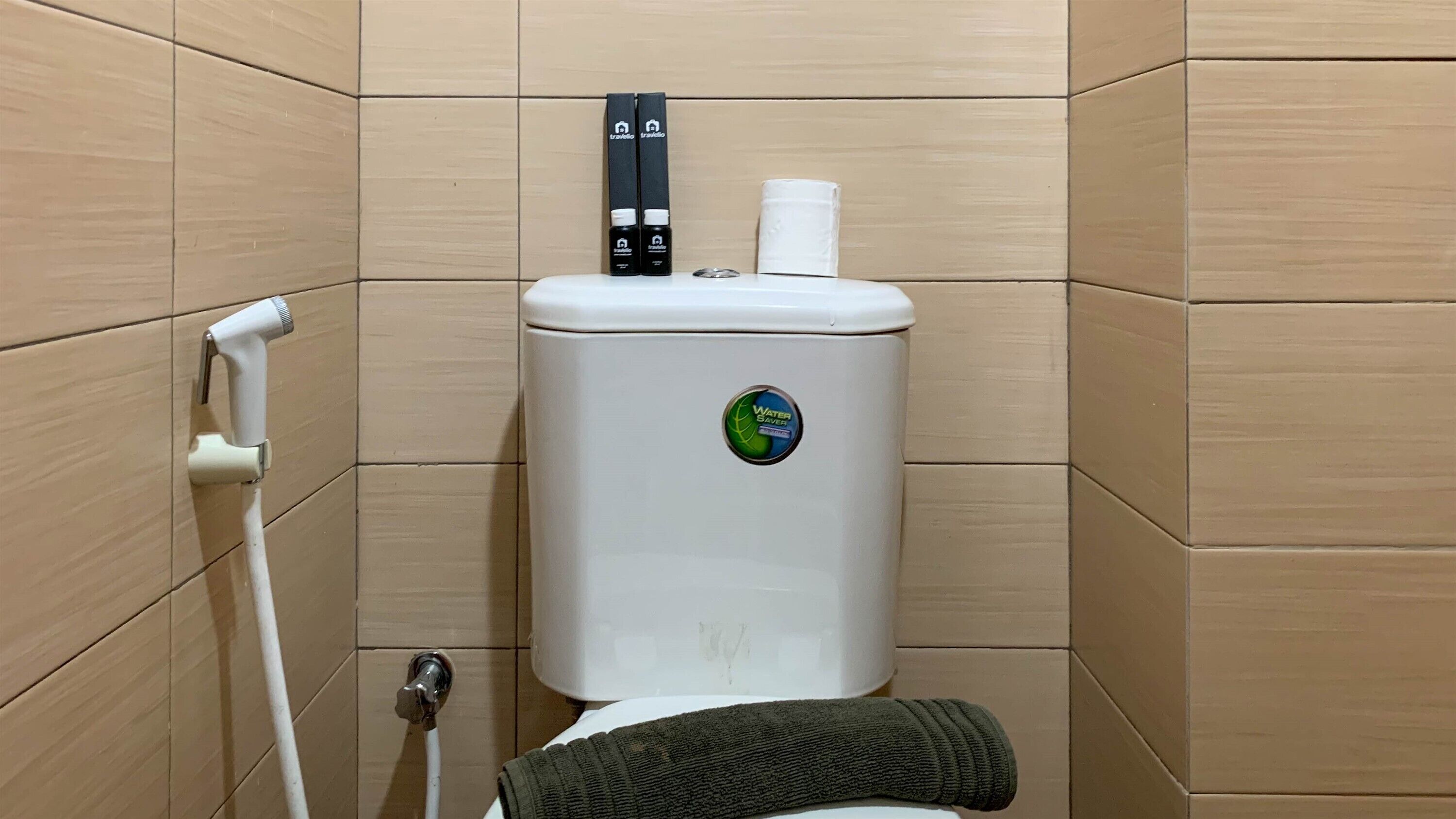 Un baño con inodoro, secamanos y dispensador de toallas de papel.
