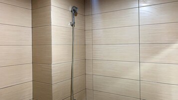 Una ducha con cabezal de ducha manual y manguera flexible.