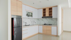 Una cocina moderna con armarios blancos, un refrigerador de acero inoxidable y un protector contra salpicaduras de mármol.