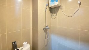 Moderni kylpyhuone, jossa on beigenväriset laatat, wc-istuin, jossa on bidee-suihku, ja seinään kiinnitetty suihku.