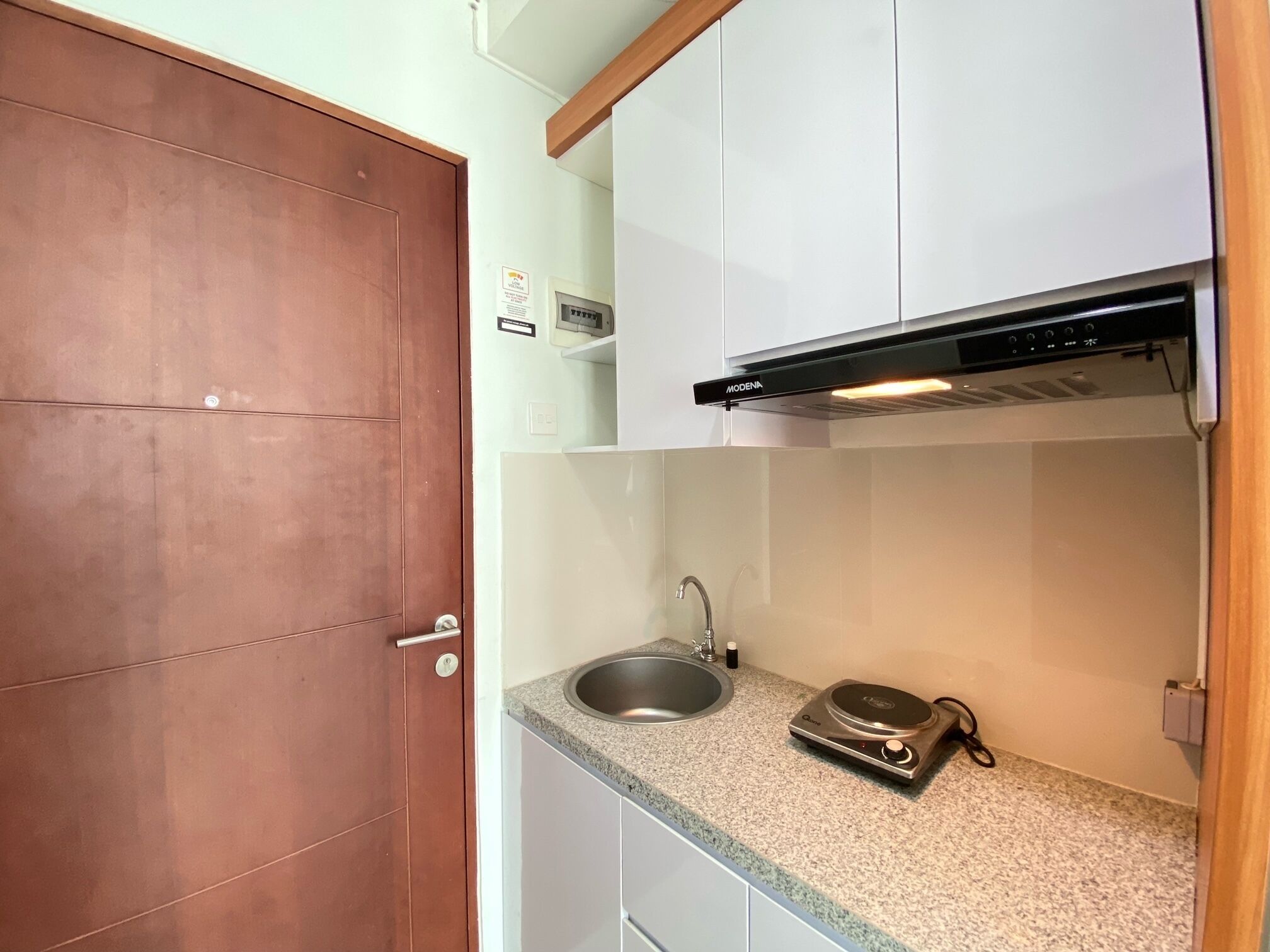 A compact kitchen with a stainless steel sink, a built-in microwave, and a black range hood.