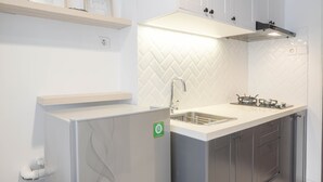 Eine moderne Küche mit weißen Schränken, einer Rückwand mit Fischgrätmuster, einer integrierten Spüle und einer Edelstahl-Dunstabzugshaube.