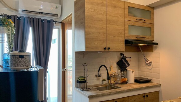 A modern kitchen with wooden cabinets, a built-in oven, and a stainless steel sink. - Comfort And Nice 2Br At Cinere Resort Apartment (Depok)