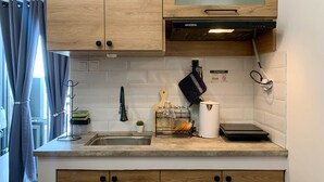 A modern kitchen with wooden cabinets, a built-in microwave, and a stainless steel sink. - Comfort And Nice 2Br At Cinere Resort Apartment (Depok)