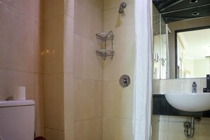Bathroom features a toilet, shower, and sink with a mirror above.