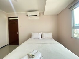 Habitación de hotel con cama, ventana, aire acondicionado y puerta.