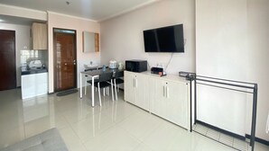 Una cocina moderna con comedor, televisor de pantalla plana montado en la pared y kitchenette con estufa y pileta.