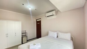 Una habitación de hotel con cama, armario, una mesita y aire acondicionado.