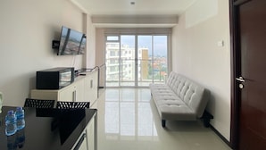 Una sala de estar moderna con un sofá, un televisor montado en la pared y un balcón con vistas a la ciudad.