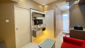 Un espacio habitable compacto con kitchenette, un sofá rojo y una pequeña mesa.