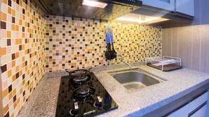 Una cocina con estufa negra, pileta y salpicadero de azulejos.