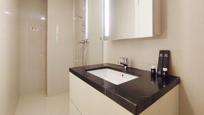 A modern bathroom with a black marble sink, a large mirror, and a shower area. - Elegant And Homey Studio At Marquis De Lafayette Apartment (Semarang)