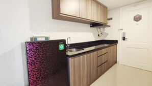 A kitchen with wooden cabinets, a black countertop, and a built-in sink. - Elegant And Homey Studio At Marquis De Lafayette Apartment (Semarang)