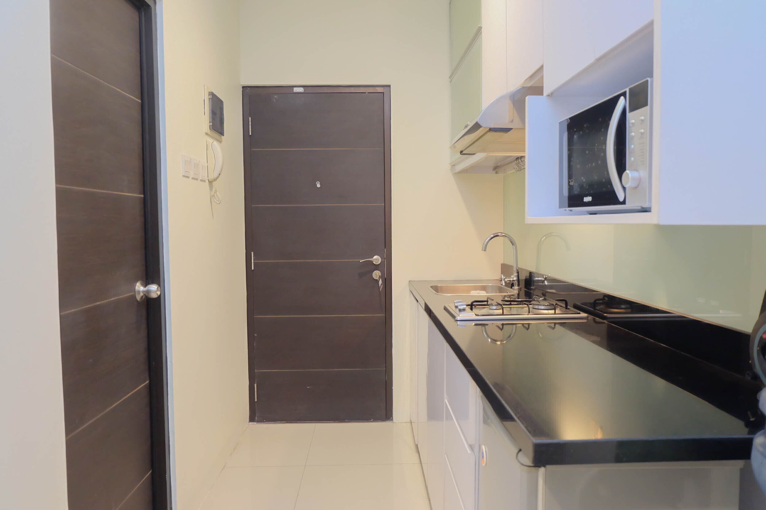 A compact kitchen with a dark door, a built-in microwave, and a sink.