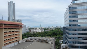 Un edificio moderno de gran altura con fachada de vidrio, estacionamiento subterráneo y vistas a un paisaje urbano con diversos edificios y zonas verdes.