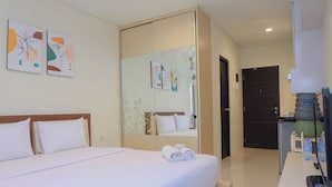 Habitación de hotel con cama, escritorio, espejo y obras de arte en las paredes.