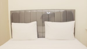 Un lit avec une tête de lit et deux oreillers.