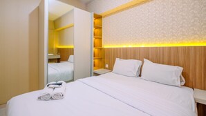 A hotel room with a neatly made bed, a large mirror, and a wooden headboard. - Well Designed 2Br Apartment At Springlake Summarecon Bekasi (Bekasi)