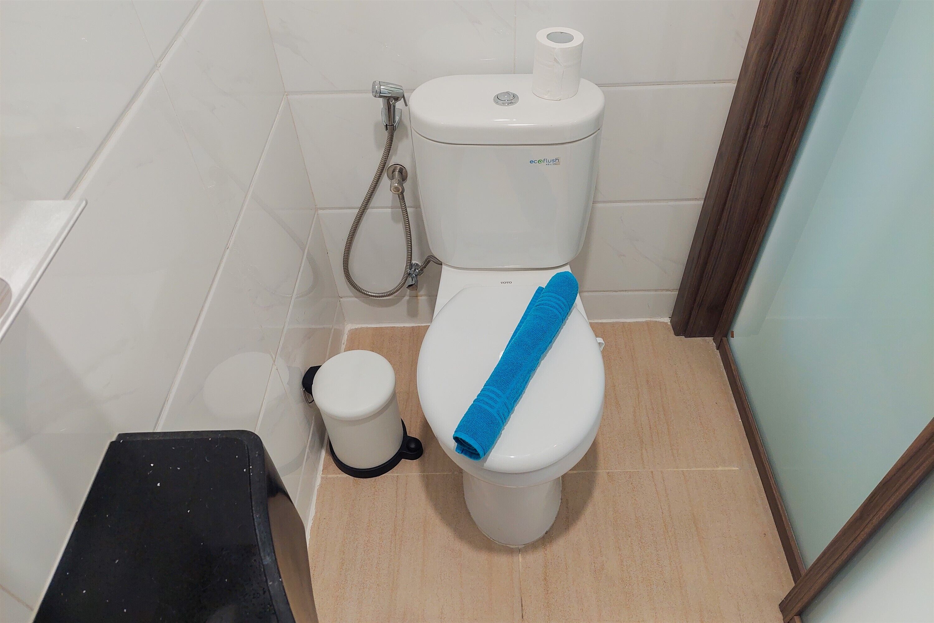 Un baño con inodoro, bidé y un pequeño cubo de basura.