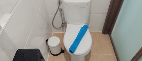 Un baño con inodoro, bidé y un pequeño cubo de basura.