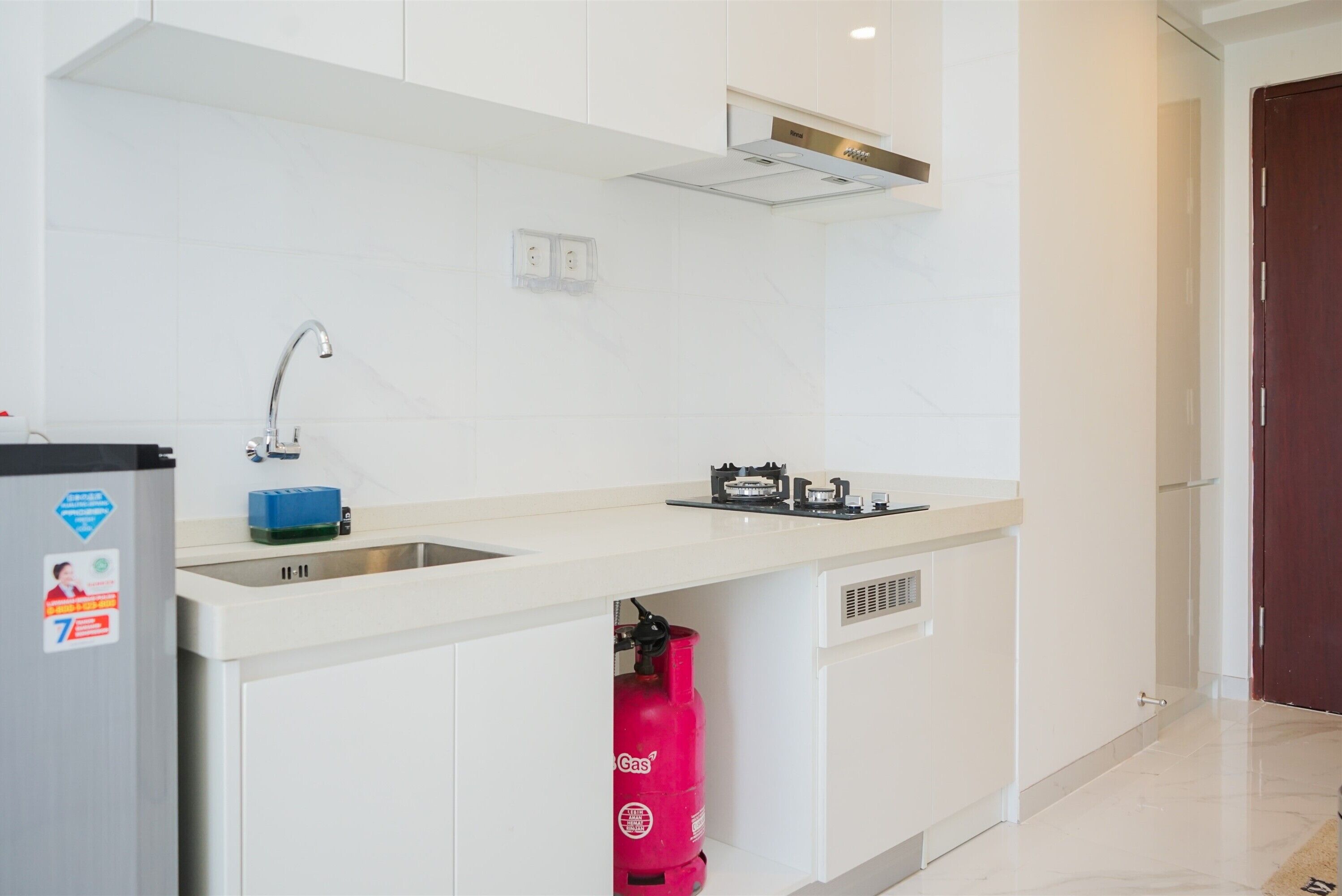 A modern kitchen with a built-in sink, a gas stove, and a red fire extinguisher.