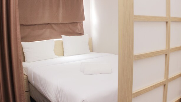 A neatly made bed with white linens and a brown headboard.