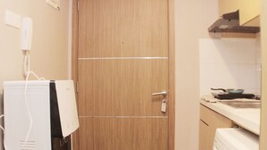 A small kitchen with a wooden door, a white stove, and a white countertop.